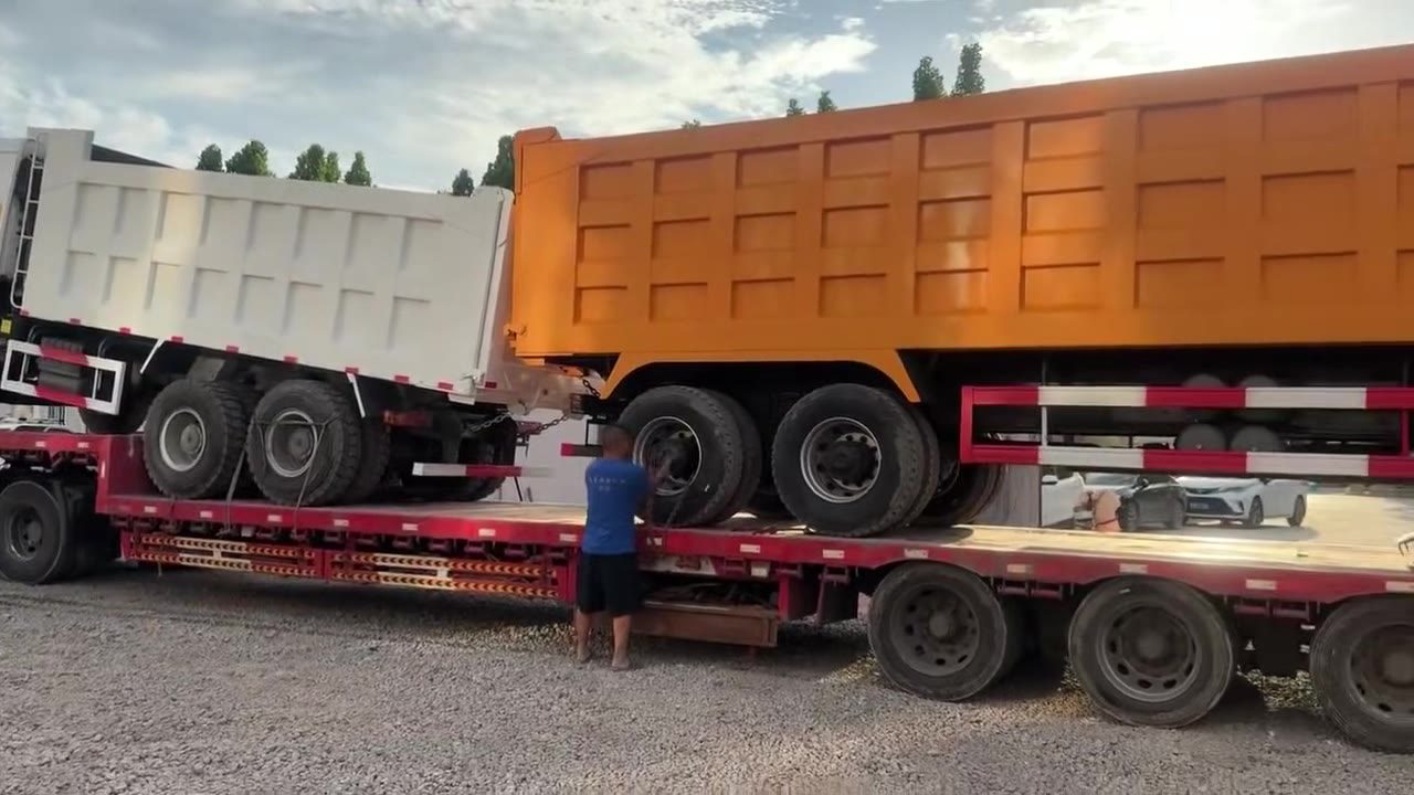 HOWO and SHACMAN dump trucks loaded on a lowbed trailer for export from Jiaxiang