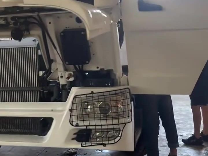 HOWO truck with the cab tilted showing the radiator and front of the engine during inspection